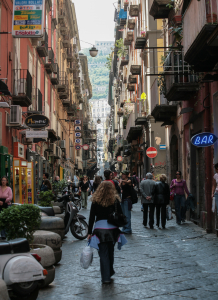 Eine belebte Straße in den spanischen Vierteln (Quartieri Spagnoli) von Neapel. Die Viertel sind ein charakteristisches Labyrinth aus engen Gassen und hohen Wohnhäusern und gelten als das Herz der Stadt. Die spanischen Viertel  sind bekannt für ihr lebendiges, authentisches neapolitanisches LebenDie Gassen sind oft mit Wäscheleinen überspannt und es herrscht reges Treiben mit kleinen Geschäften, Bars und Menschen auf der Straße. Die Viertel wurden im 16. Jahrhundert unter spanischer Herrschaft erbaut, ursprünglich als militärische Garnison zur Unterbringung spanischer Soldaten