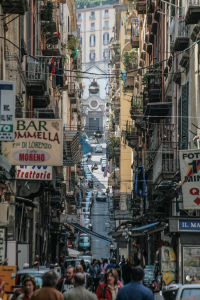 Eine belebte Straße in den spanischen Vierteln (Quartieri Spagnoli) von Neapel. Die Viertel sind ein charakteristisches Labyrinth aus engen Gassen und hohen Wohnhäusern und gelten als das Herz der Stadt. Die spanischen Viertel  sind bekannt für ihr lebendiges, authentisches neapolitanisches LebenDie Gassen sind oft mit Wäscheleinen überspannt und es herrscht reges Treiben mit kleinen Geschäften, Bars und Menschen auf der Straße. Die Viertel wurden im 16. Jahrhundert unter spanischer Herrschaft erbaut