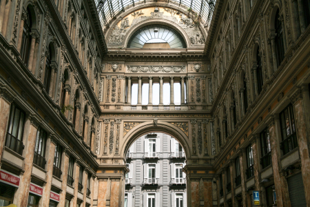 die Galleria Umberto I, eine bekannte, überdachte Einkaufsgalerie in Neapel, Italien. Standort: Die Galerie befindet sich im Herzen von Neapel, direkt gegenüber dem berühmten Opernhaus Teatro San Carlo.Architektur: Sie wurde in den Jahren 1887 bis 1890 erbaut und ist für ihre imposante Glas- und Eisenkuppel sowie die eleganten Marmorböden mit Mosaikmustern bekannt. Die Haupteingänge sind durch elegante Bögen und beeindruckende Verzierungen gekennzeichnet.Atmosphäre: Die Galerie ist ein beliebter Treffpunkt und beherbergt Geschäfte, Cafés und Büros. Da es sich um einen öffentlich zugänglichen Raum handelt, ist der Eintritt frei.